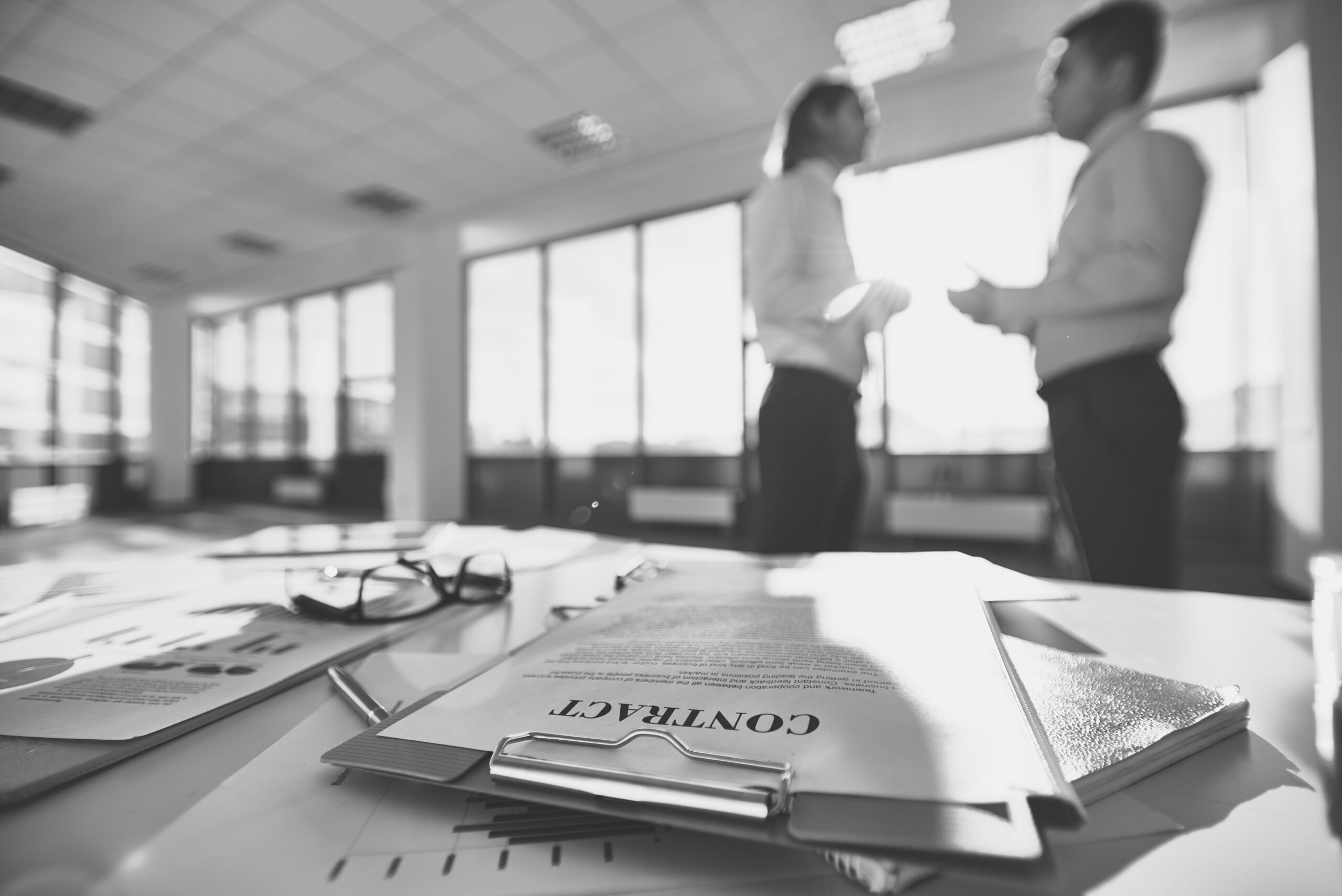 Business papers on the desk and two men communicating on background